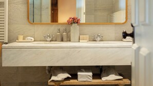 A bathroom with a double sink, a large mirror with a gold frame, and a wooden shelf with towels. - Quinta Nova Winery House Relais & Châteaux (Santa Maria da Feira)