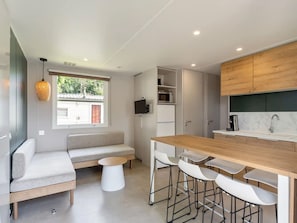 Eine moderne Küche mit Holztischplatte, weißen Barhocker, integriertem Mikrowellenherd und einer Sitzecke mit Sofa und Couchtisch.