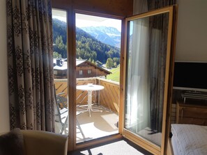 A room with a sliding glass door leading to an outdoor balcony with a table and chairs. - Appartements Alpin Live, (Samnaun-Laret) by Interhome (Samnaun)