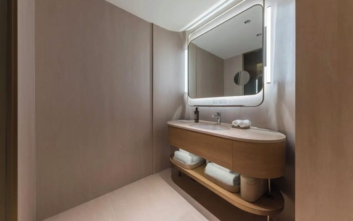 A modern bathroom with a vanity, mirror, and towel rack.