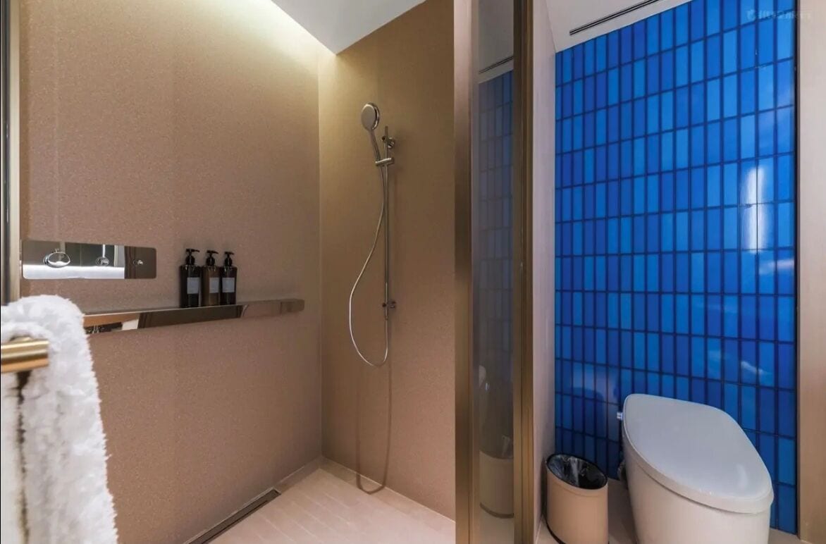 A bathroom with a shower, toilet, and a sink with soap dispensers.