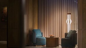 Una habitación con dos sillones, una mesita y una lámpara de pie alta.
