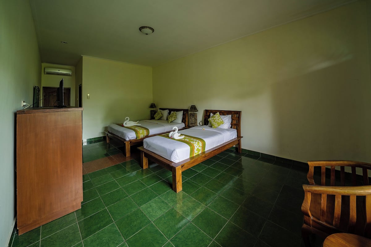 A hotel room with two beds, a wooden desk, and a chair.