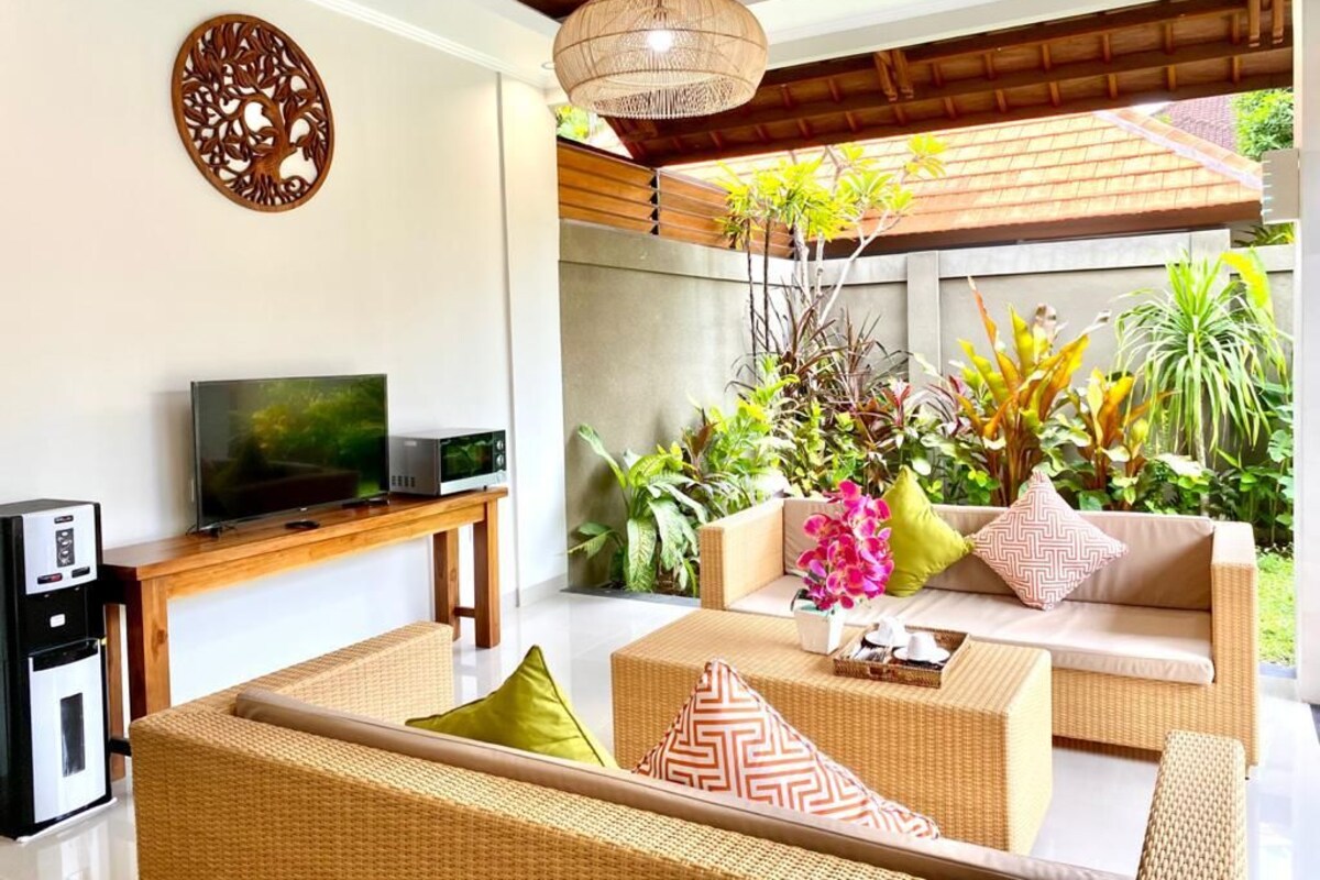 A modern living room with wicker furniture, a flat-screen TV, and a coffee machine.
