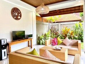A modern living room with wicker furniture, a flat-screen TV, and a coffee machine. - Three Brothers Bungalows and Villas (Legian)