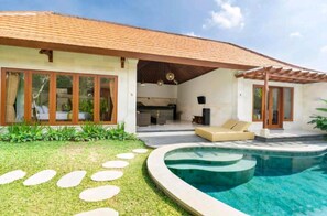 Een modern huis met een zwembad, terras en tuin.