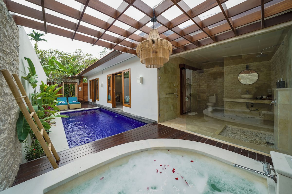 A spa area with a hot tub, a swimming pool, and a glass-enclosed shower.