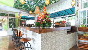 A bar area with a patterned wall, hanging lights, and a decorative plant arrangement. - Three Brothers Bungalows and Villas (Legian)