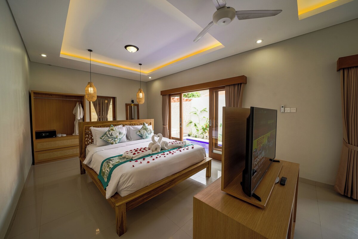 A modern hotel room with a wooden bed, a television, and a ceiling fan.