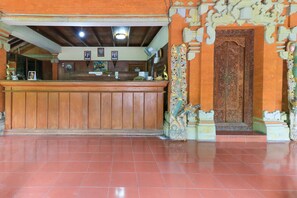 A reception area with a wooden counter, a tiled floor, and a decorative door with intricate carvings.