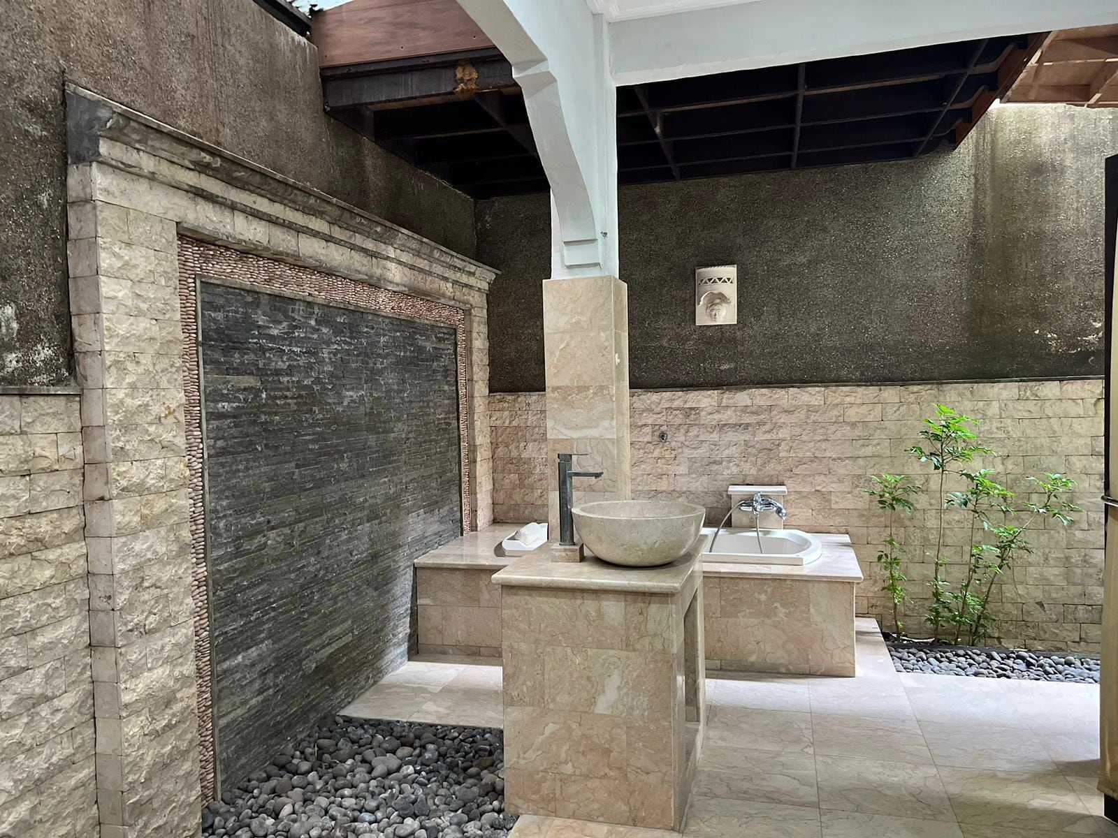 A modern bathroom with a large stone sink, a separate basin, and a built-in shower area.