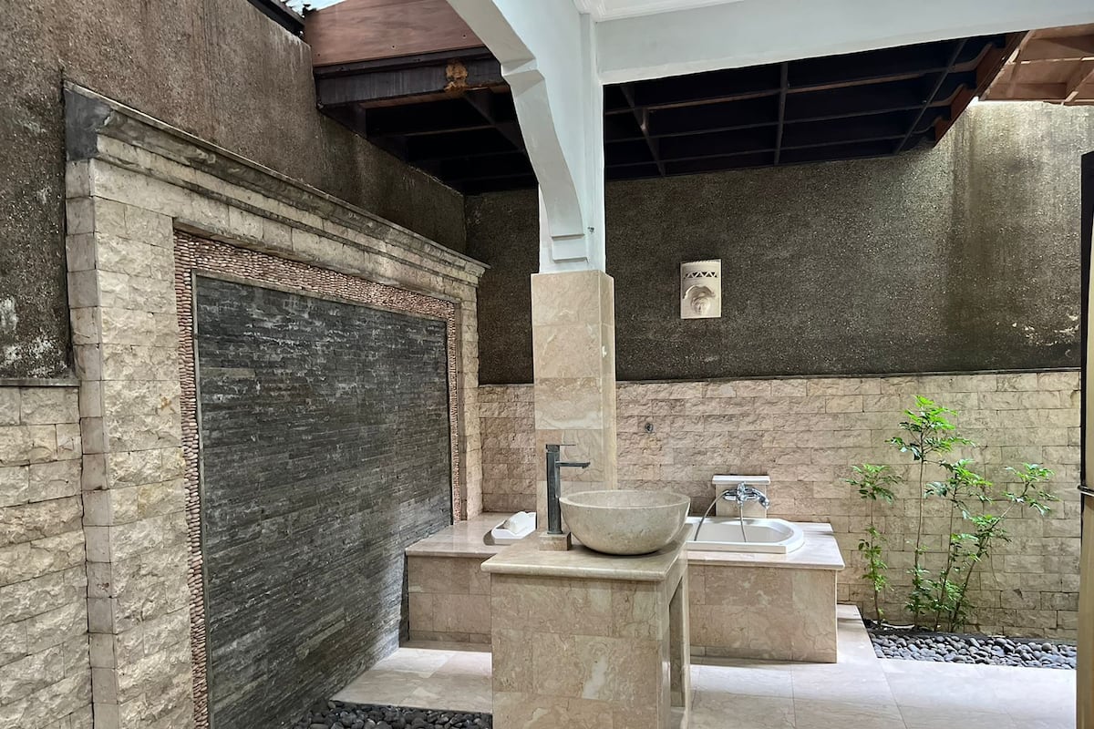 A modern bathroom with a large stone sink, a separate basin, and a built-in shower area.