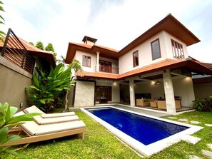 A two-story house with a swimming pool, outdoor seating, and a covered patio area.