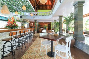 A spacious indoor area with a bar, multiple seating arrangements, and a balcony with greenery. - Three Brothers Bungalows and Villas (Legian)