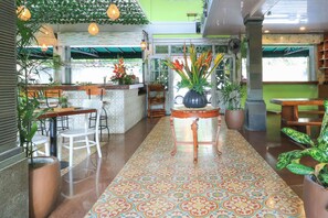 A restaurant with a tiled floor, wooden furniture, and potted plants. - Three Brothers Bungalows and Villas (Legian)