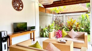 A modern living room with wicker furniture, a flat-screen TV, and a coffee machine. - Three Brothers Bungalows and Villas (Legian)