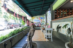 Een restaurant met terras, een decoratieve boom en een patroonmuur.