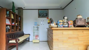 A reception desk with a wooden finish, a bench, a shelf with various items, and a framed picture on the wall.