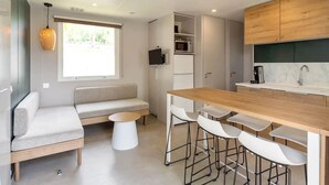 Eine moderne Küche mit Holztischplatte, weißen Barhocker, integriertem Mikrowellenherd und einer Sitzecke mit Sofa und kleinem runden Tisch.