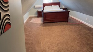 Une chambre à coucher avec un lit en bois, une table de chevet, un petit tapis et une fenêtre avec des stores.