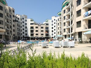 A hotel with multiple balconies, a swimming pool, and outdoor seating areas. - Avalon Apartments (Nessebar)