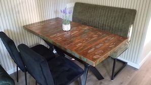 Et spisebord med træplade og en grøn polstret bænk.