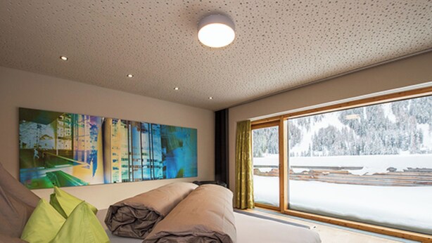 Una camera da letto moderna con un'ampia finestra, un letto con cuscini e un quadro appeso al muro.