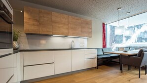 Una cucina moderna con mobili in legno, un lavello in acciaio inossidabile e un'area pranzo con tavolo e sedie.