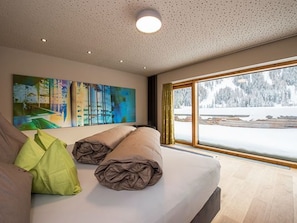 A modern bedroom with a large window, a bed with pillows, and a painting on the wall. - Das Felaria, (Samnaun-Laret) by Interhome (Samnaun)