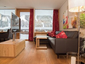 A modern living room with a sofa, TV, wooden coffee table, and a dining area with chairs. - Das Felaria, (Samnaun-Laret) by Interhome (Samnaun)