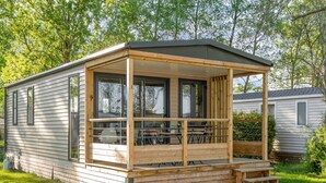 En campingvogn med en overdækket veranda, et bord og en bænk.