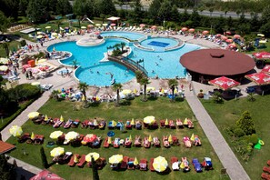 Una gran piscina al aire libre con varias secciones, rodeada de numerosas tumbonas y sombrillas.