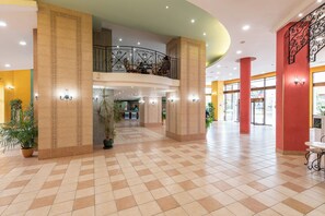 A spacious lobby with a checkered floor, a central column, and a balcony with ornate railings. - Hrizantema (Nessebar)