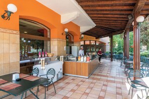 An outdoor cafe area with a counter, seating, and a view of the street. - Hrizantema (Nessebar)