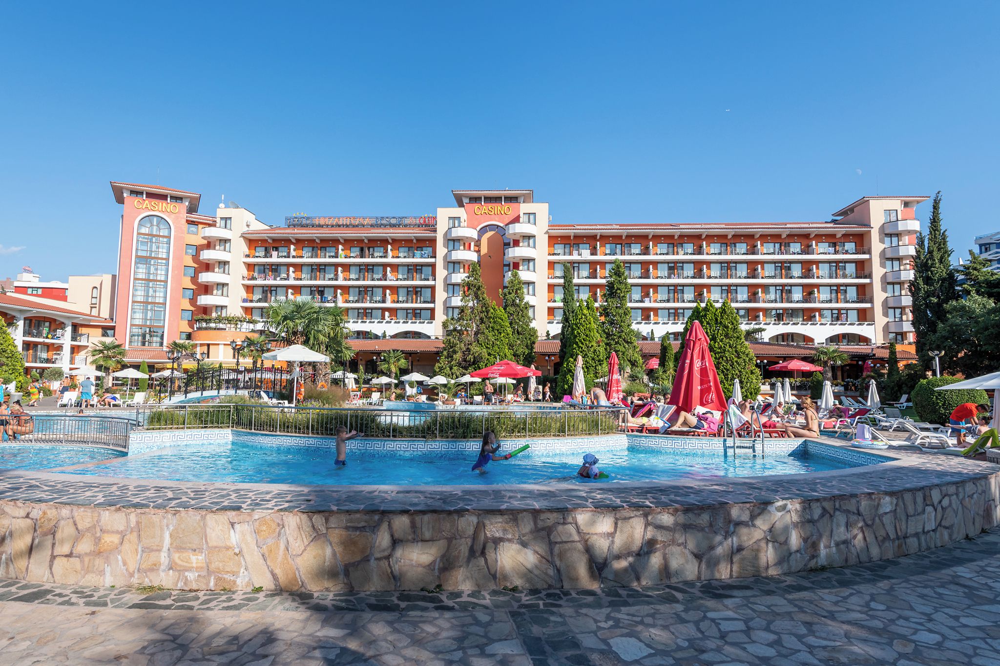 A hotel with a swimming pool, multiple balconies, and a casino sign.