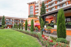 A hotel with a casino sign, outdoor seating, and a well-maintained garden. - Hrizantema (Nessebar)
