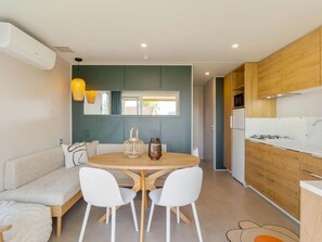 Une cuisine moderne avec des meubles en bois, une table de salle à manger ronde entourée de chaises blanches et une cuisinière encastrée.