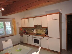 A compact kitchen with white cabinets, a wooden countertop, and a window with curtains. - Tschlin Chasa La Resgia, (Tschlin) by Interhome (Tschlin)
