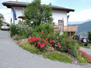 A house with a garden, a parked car, and mountains in the background. - Tschlin Chasa La Resgia, (Tschlin) by Interhome (Tschlin)