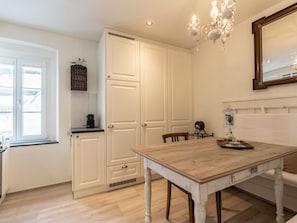 A kitchen with white cabinetry, a wooden dining table, and a chandelier. - Zollhaus, (Vnà) by Interhome (Vnà)