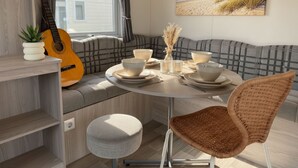 Ein gemütlicher Essbereich mit einem Tisch für vier Personen, einer Gitarre und einem Gemälde mit Strandblick.