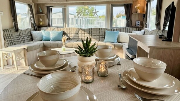 Ein modernes Wohnzimmer mit einer Couch, einem Esstisch gedeckt mit Schüsseln und Tellern und Blick ins Freie.