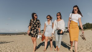 Ein Sandstrand mit vier Personen, die spazieren gehen.