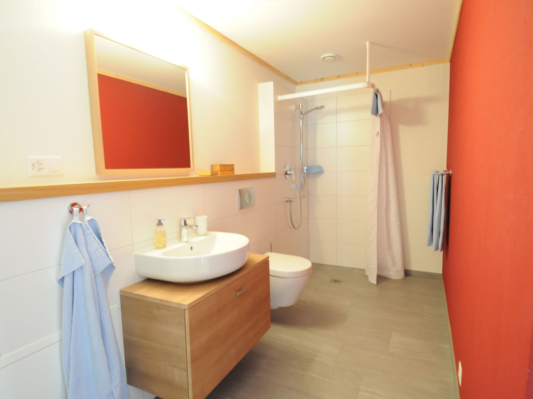 Et moderne badeværelse med et stort spejl, en vask, et toilet og en bruseniche.