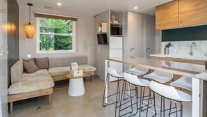Uma cozinha moderna com bancada de madeira, banquetas brancas e micro-ondas embutido.