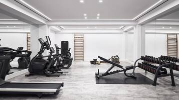 Un gimnasio moderno con cintas de correr, elípticas y bancos de pesas.
