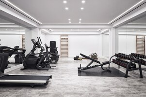 Un gimnasio moderno con cintas de correr, elípticas y bancos de pesas.