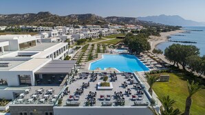 A resort with a swimming pool, outdoor seating, and a view of the beach and mountains. - Atlantica Beach Resort (Kos)