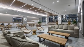 A modern lounge area with sofas, chairs, and tables, featuring a clean, contemporary design and ample seating. - Atlantica Beach Resort (Kos)