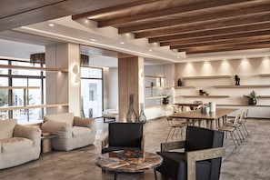 A modern interior with a wooden ceiling, a round coffee table, and a dining area with chairs and a table. - Atlantica Beach Resort (Kos)